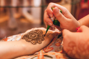 Intricate henna body art is applied to the bride in a prenuptial ceremony with her closest female friends.