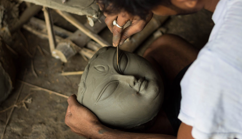 A man carves eyebrows into a religous idol.