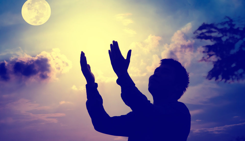 A man holding up his hands before the moon