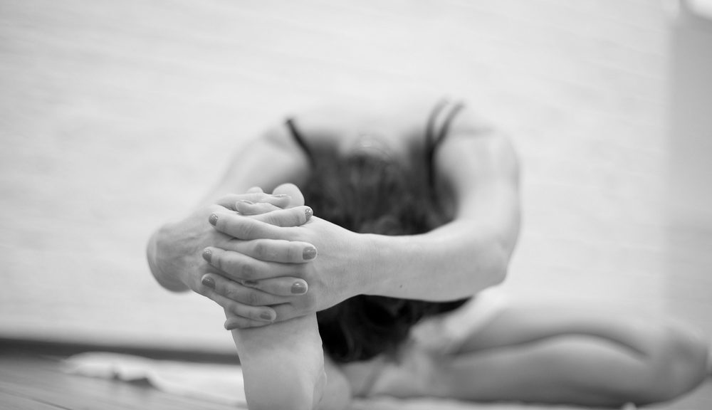 A Bikram Yoga practitioner stretched out grabbing his foot.