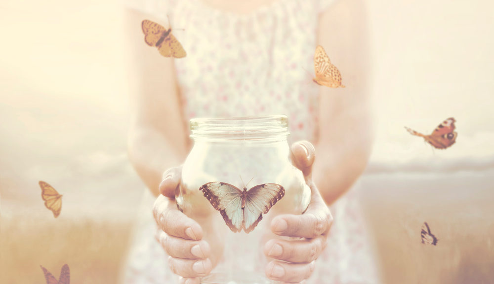 A woman holds a butterfly in a jar.