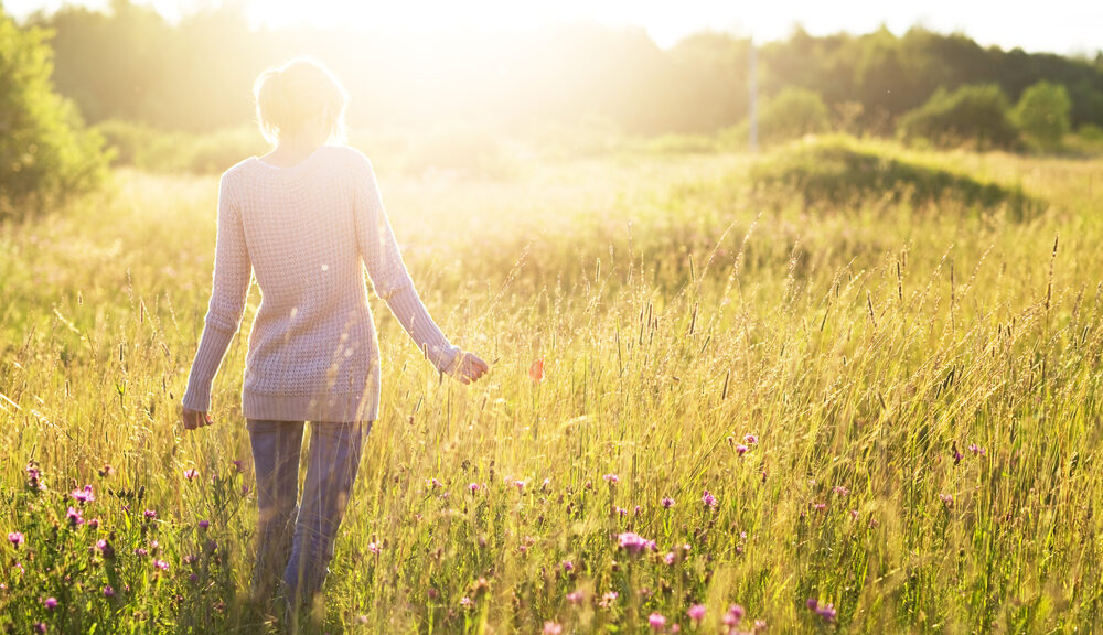 A woman participates in one of life's classic summer activities: walking through a meadow.
