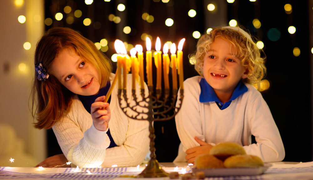 Two children light a menorah,