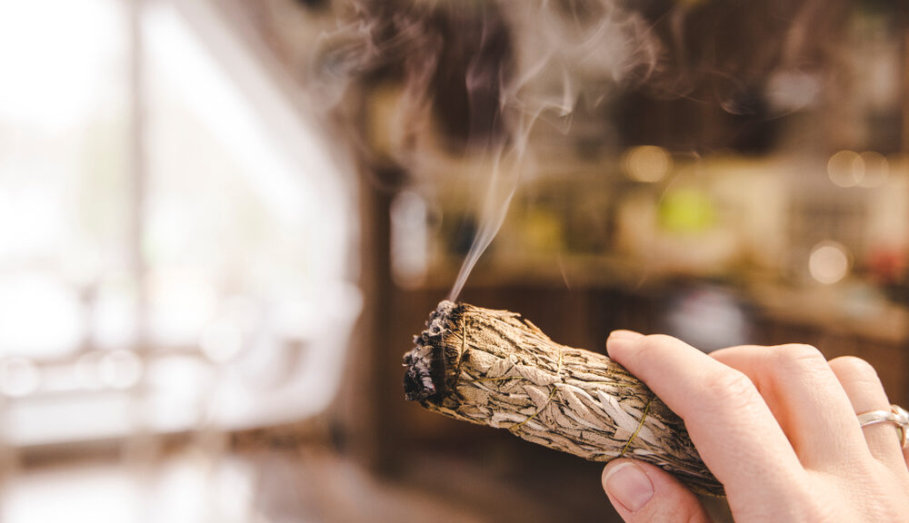 A man burns sage to cleanse a new home.