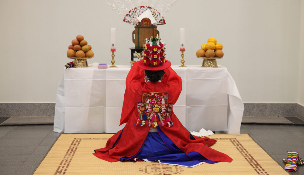 A Korean shaman kneels before a shrine.