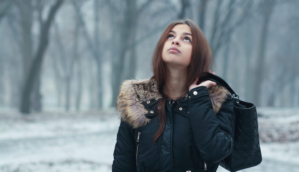 A woman walks through the snow wondering how best to avoid procrastination during the winter.