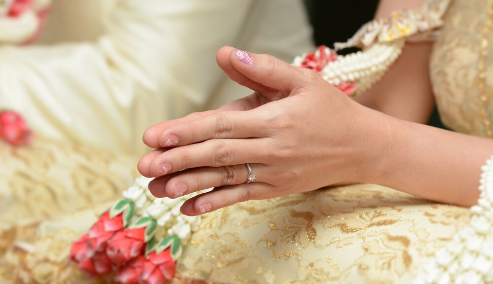 A woman clasps her hands together during an interfaith wedding ceremony.