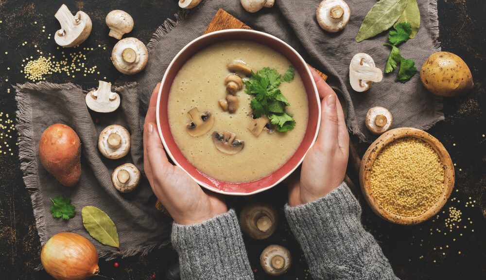 Someone holds a bowl of soup--a classic food to soothe your soul.