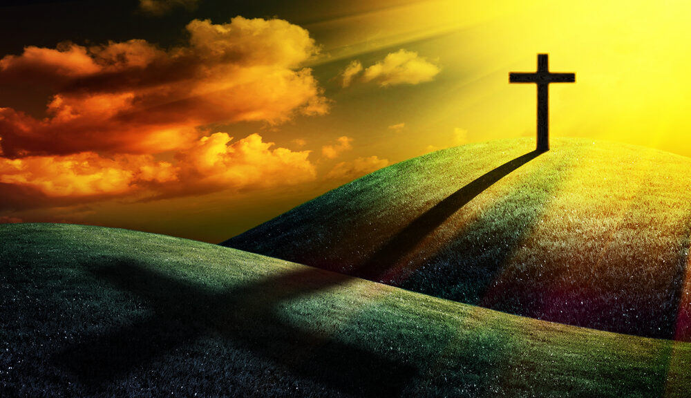 Christian cross on a hill with light beaming down