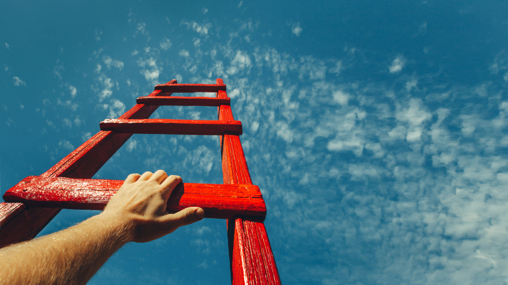 A man climbs up a ladder toward the sky.