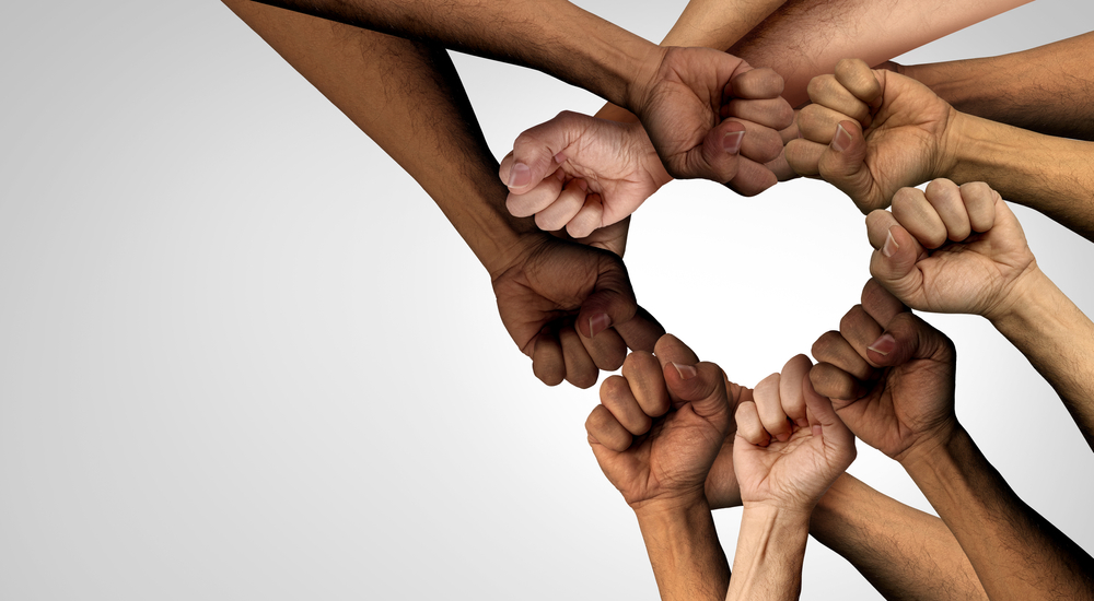 A group of hands in the shape of a heart model the season for nonviolence.
