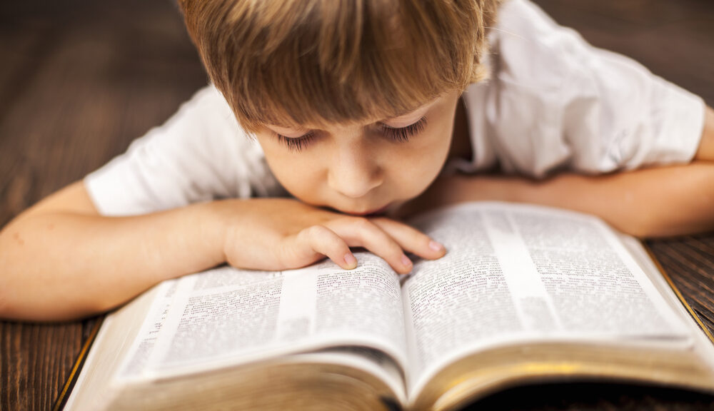 A child closely reads a book.